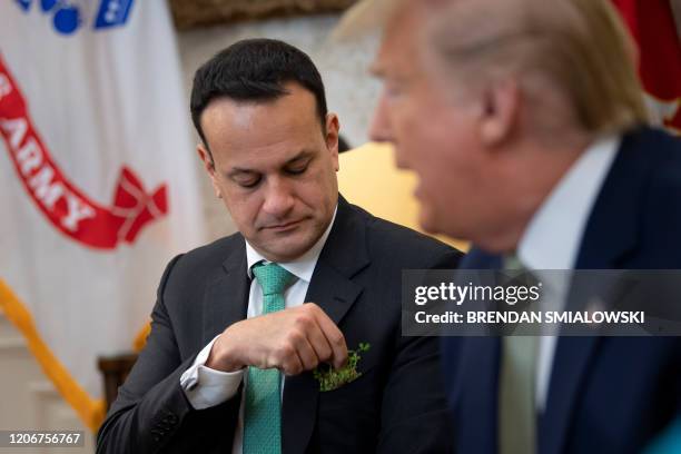 Ireland's Prime Minister Leo Varadkar adjusts his shamrock bouquet and listens while US President Donald Trump speaks to the press before a meeting...