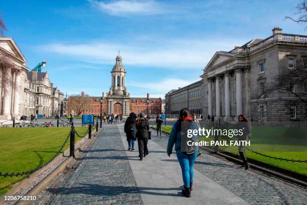 People walk around the grounds of Trinity College Dublin on March 12, 2020. - Ireland on Thursday announced the closure of all schools and colleges,...