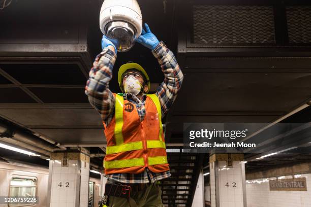 An MTA employee wearing a protective mask cleans a subway security camera at Grand Central Terminal on March 12, 2020 in New York City. U.S....