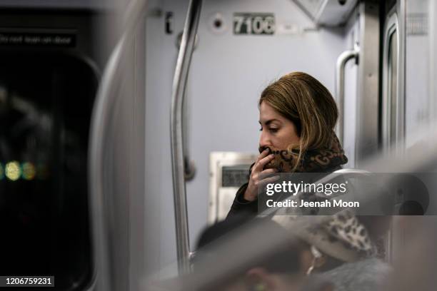 Woman wearing a protective mask sits in a subway car at Grand Central Terminal on March 12, 2020 in New York City. U.S. President Donald Trump...