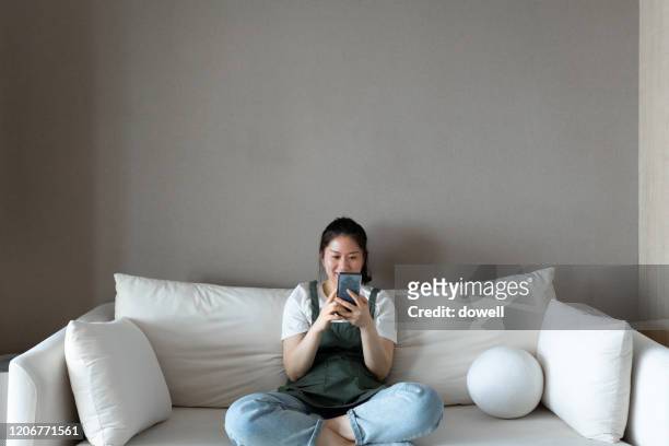 female using mobile phone on sofa - stay at home mother stock pictures, royalty-free photos & images