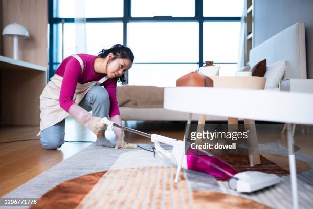 woman cleaning floor with  vacuum cleaner in living room - vacuum cleaner woman stockfoto's en -beelden
