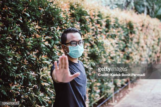southeast asia man wearing mouth mask and stop hand sign - air respirator mask stock pictures, royalty-free photos & images