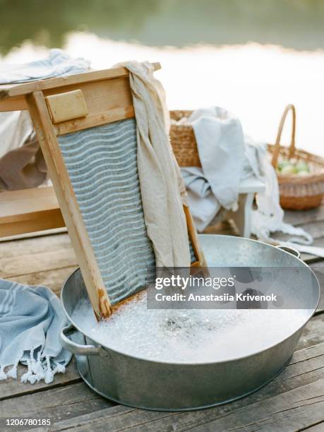 vintage still life photo of laundry with metal basin, washboard, ecological household soap near river. zero waste and rustic concept. - washboard laundry stock pictures, royalty-free photos & images