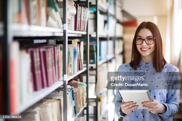 porträt von college-studenten, die in der bibliothek mit tablet-pc studieren - librarian stock-fotos und bilder