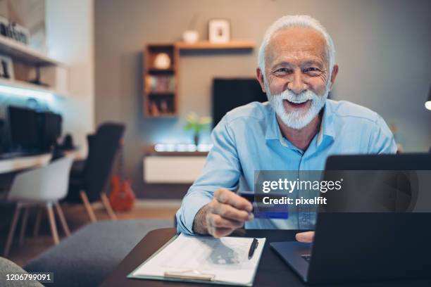 senior man shopping on-line using a credit card - silver surfer stock pictures, royalty-free photos & images