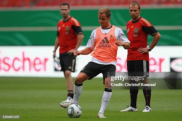 Condition coach Shad Forsythe and assistant coach Hansi Flick watch Mario Goetze shooting a ball during a training session of the German National...