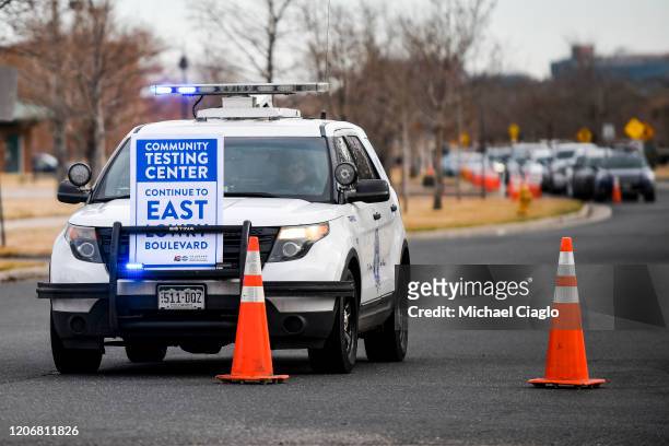 Sign directing people to Colorado's first drive-up COVID-19 testing center sits on a police car outside the Colorado Department of Public Health and...