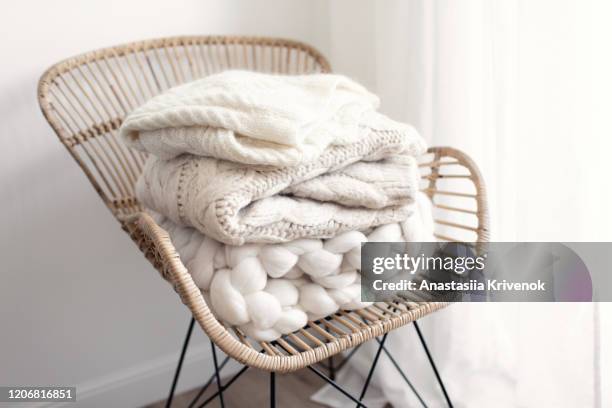 stack of cozy wool white knitted sweaters on wicker armchair. pile of merino and cashmere winter clothes. hygge style. warm concept. - cashmere stock pictures, royalty-free photos & images