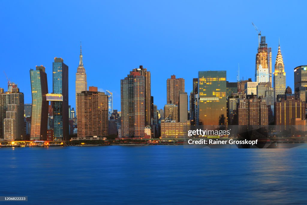 Skyline of Midtown Manhattan with the illumiated Empire State Building at dawn