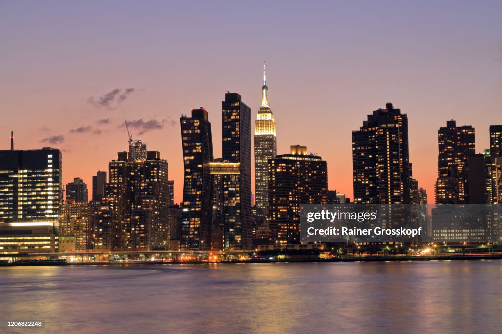 Skyline of Midtown Manhattan with the illumiated Empire State Building at sunset