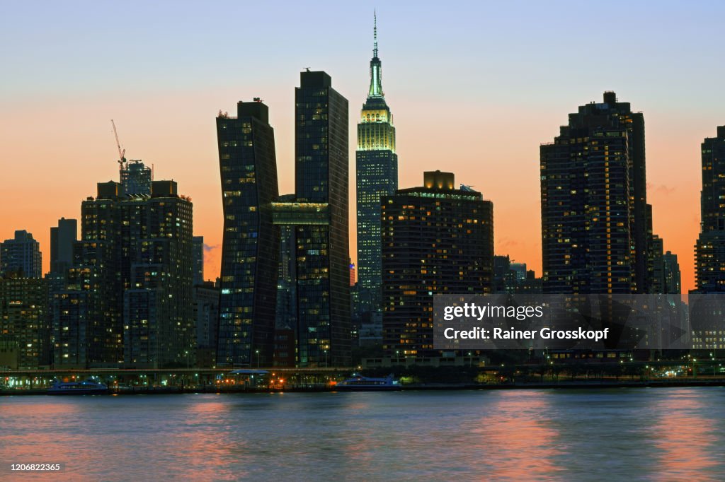 Skyline of Midtown Manhattan with the illumiated Empire State Building at sunset