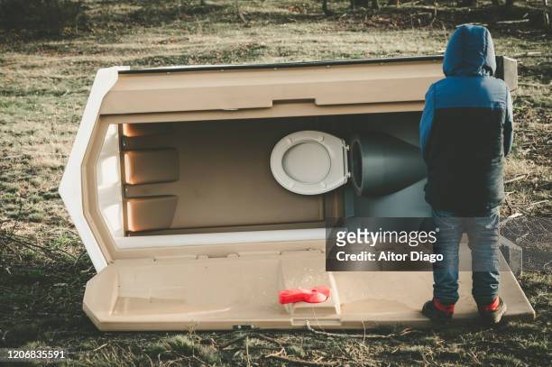 back view of a child  next to a portable toilet fallen on the ground in winter time. - child urinating stock pictures, royalty-free photos & images