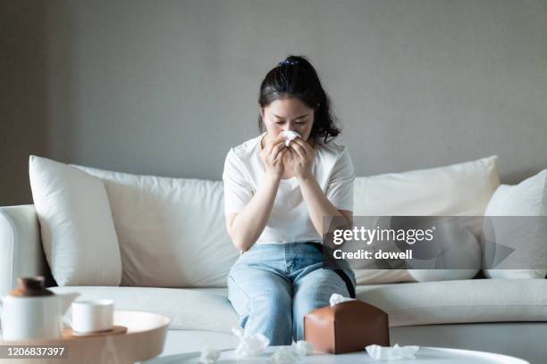 ill woman with the flu blowing her nose - アレルギー ストックフォトと画像