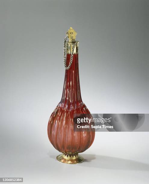 Bottle of ruby glass with flattened spherical body with vertical ribs and gilt silver frame, Conical foot of gilt silver, which with a serrated edge...