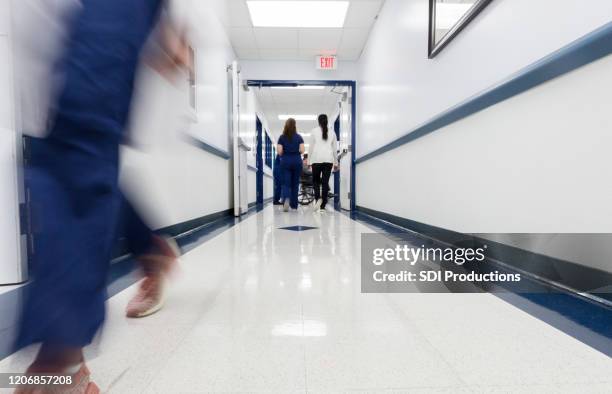 low-winkel-ansicht belebt krankenhaus korridor mit nicht erkennbaren laufenden krankenschwester - linoleum stock-fotos und bilder