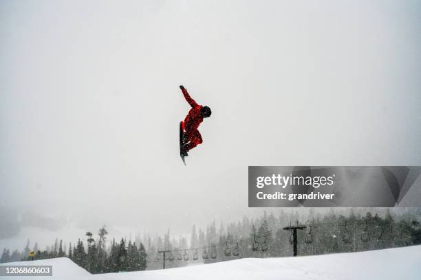 a young male snowboarder coming off a jump at a ski area in colorado on a snowy day - snowboard jump close up stock pictures, royalty-free photos & images