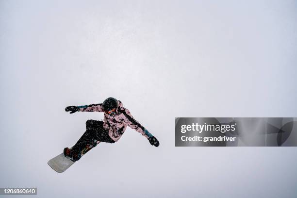 a young male snowboarder coming off a jump at a ski area in colorado on a snowy day - snowboard jump close up stock pictures, royalty-free photos & images