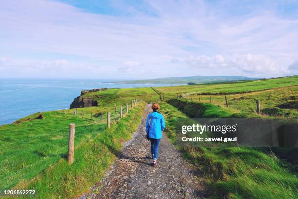 frau trekking auf cliffs of moher wanderweg in irland - irishman stock-fotos und bilder