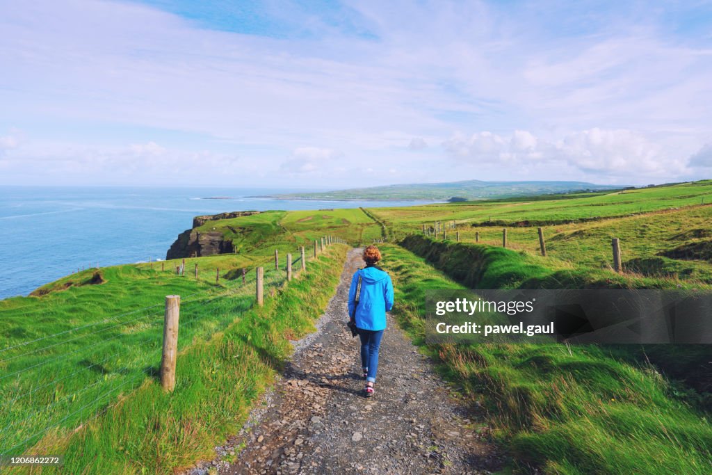 Woman trekking on Cliffs of Moher walking trail in Ireland
