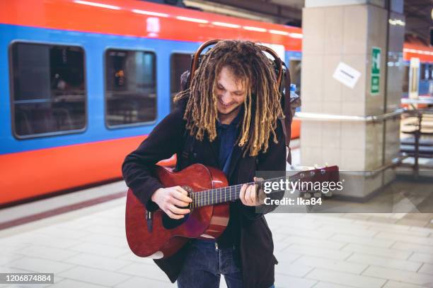 ung man spelar akustisk gitarr på tågstationen - performer bildbanksfoton och bilder