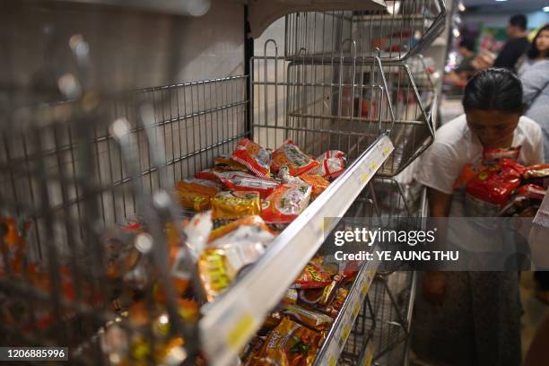 This photo taken on March 12, 2020 shows a woman buying packets of instant noodles as people panic buy groceries in a supermarket, after hearing...