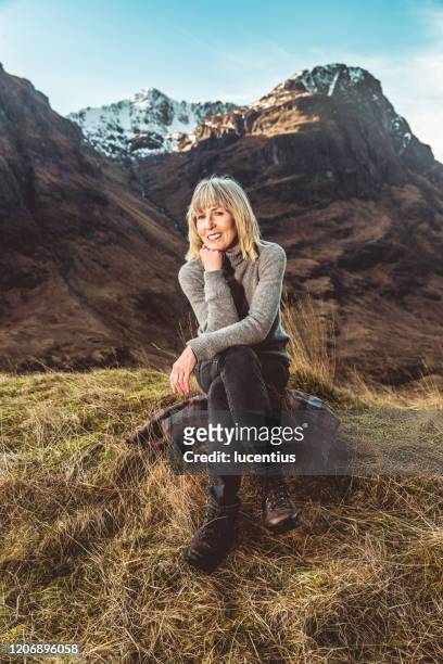 mature woman relaxing in glencoe scotland - legs crossed at knee stock pictures, royalty-free photos & images
