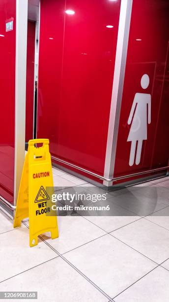 caution slippery surface sign on wet floor at the entrance to the women's toilet - opgepast-gladde-vloer stockfoto's en -beelden