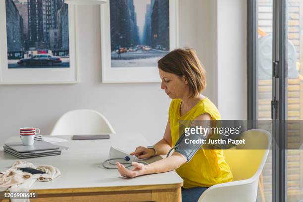woman checking blood pressure - blood pressure stock-fotos und bilder