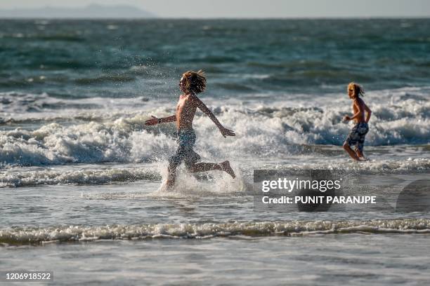 Foreign youth enjoy the sea on the beach in Goa on March 13, 2020.