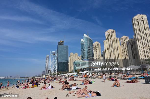 Picture taken on March 13, 2020 shows people on the beach in the area of the Jumeirah Beach residence in Dubai.