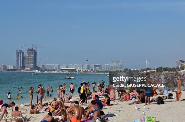Picture taken on March 13, 2020 shows people on the beach in the area of the Jumeirah Beach residence in Dubai.