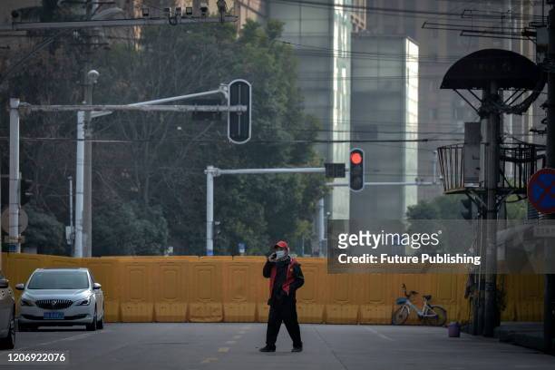 Guard walks by the temporary wall blocking a road in Wuhan in central China's Hubei province Thursday, March 12, 2020.- PHOTOGRAPH BY Feature China /...