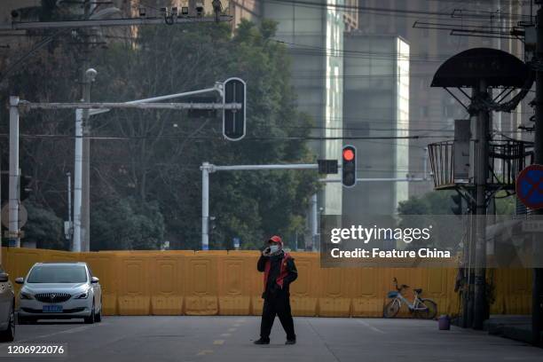 Guard walks by the temporary wall blocking a road in Wuhan in central China's Hubei province Thursday, March 12, 2020.- PHOTOGRAPH BY Feature China /...