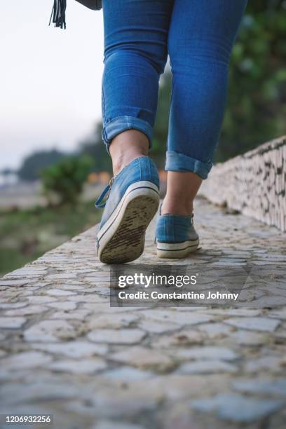 rear view of woman legs in sneakers walking - teen soles stock pictures, royalty-free photos & images