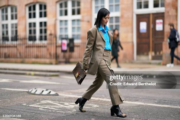 Freya Sinyu Siu wears a white shirt, a beige oversized blazer jacket, a chain belt, flared pants, black leather boots from Balenciaga, a Vuitton bag,...