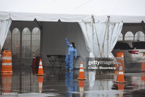 Health care worker in a protective suit gestures inside a six lane COVID-19 drive-through testing facility at Glen Island Park in New Rochelle, New...