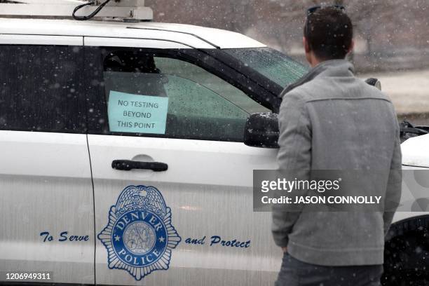 Man talks with a Denver Police officer when arriving at a drive-up testing site the coronavirus run by the Colorado Department of Health and...