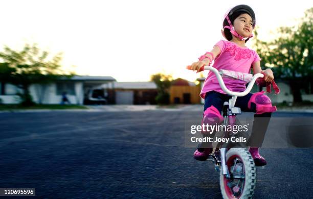 girl riding bicycle on street - roupa desportiva de protecção imagens e fotografias de stock