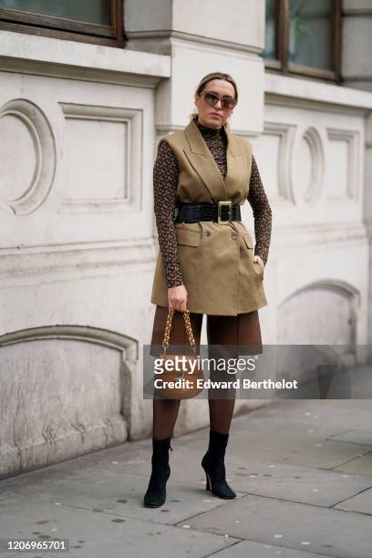 Camila Carril wears mirror sunglasses, a Burberry monogram brown turtleneck top, a sleeveless beige blazer jacket, a black leather large belt with...