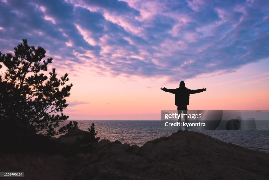 Junger Mann erhebt handundert es am Berg