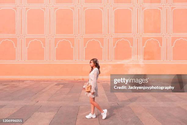 young lady walk along painted pink wall of jaipur city palace, rajasthan, india - jaipur stock-fotos und bilder