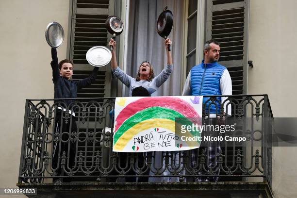 Family plays lids of pots and pans from balcony of their home where there is a banner reading 'Everything will be fine' in the neighborhood San...