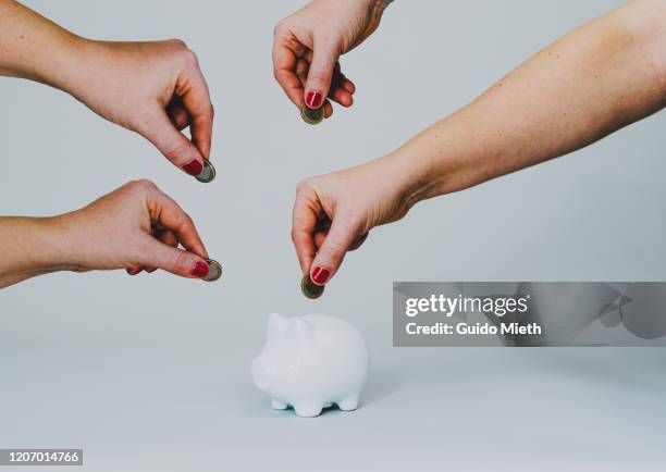 hands putting a coin in a white piggy bank. - inserting stock pictures, royalty-free photos & images