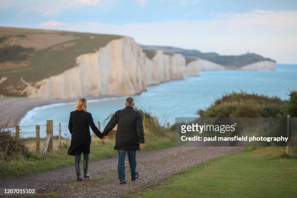 couple walking towards seven sisters coastline - east sussex imagens e fotografias de stock