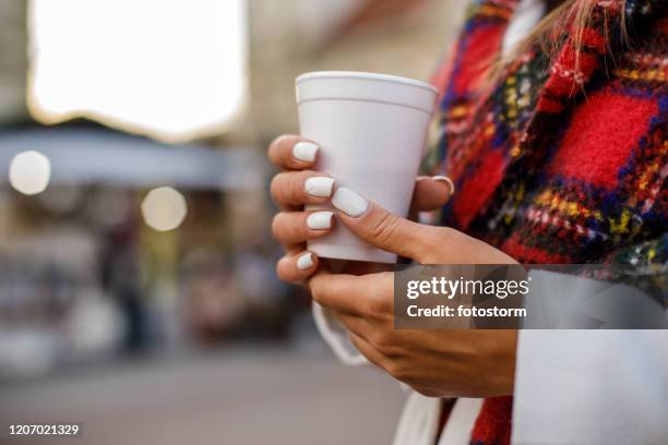 manos femeninas suaves sosteniendo una taza de plástico - white nail polish fotografías e imágenes de stock