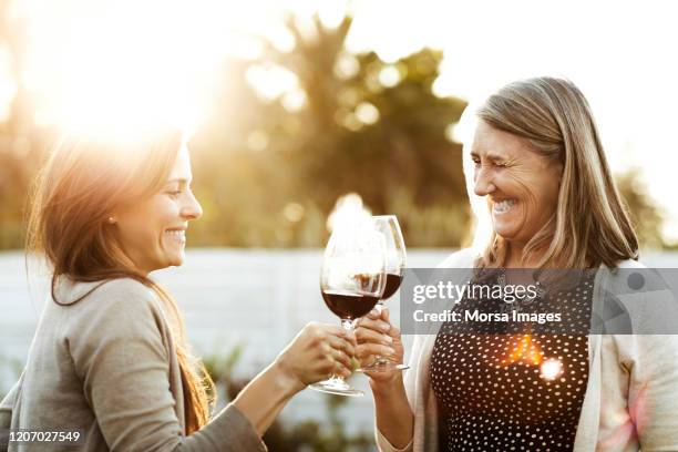 lächelnde mutter und tochter toasten weingläser - drinking wine stock-fotos und bilder