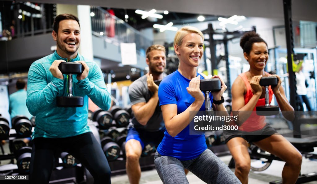 Group of young happy fit people doing exercises in gym