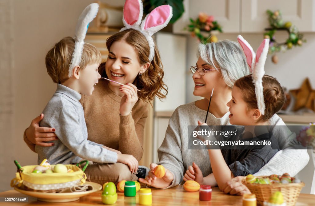 Happy easter! family mother, grandmother and children paint eggs for holiday