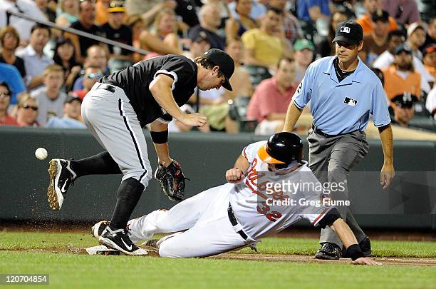 Matt Wieters of the Baltimore Orioles slides safely into third base, knocking the ball away from Brent Morel of the Chicago White Sox at Oriole Park...